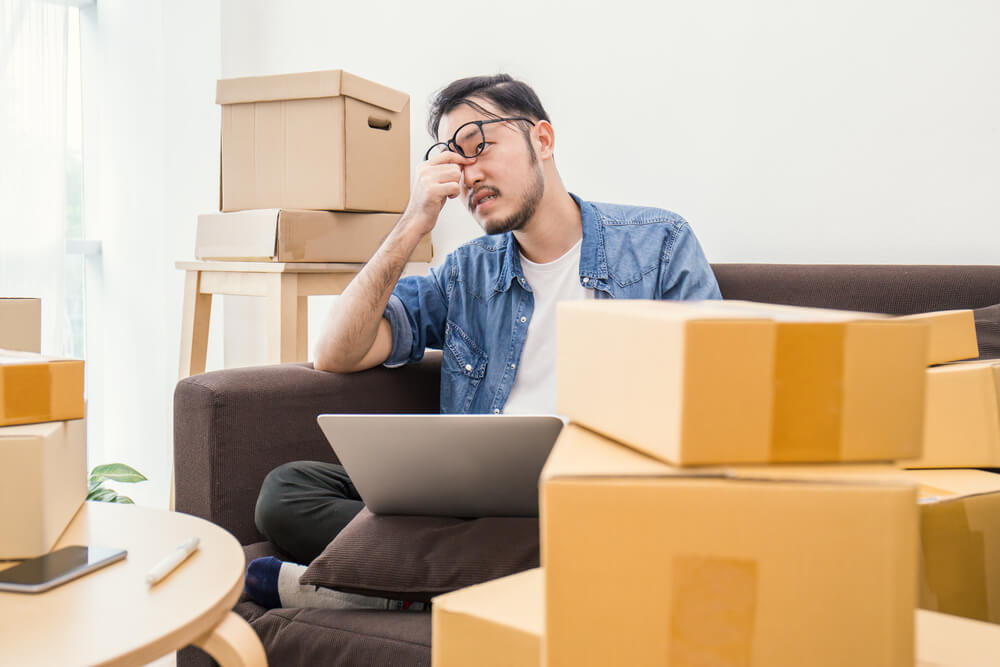 step-step-guide-selling-your-residential-property-malaysia/step-step-guide-selling-your-residential-property-malaysia-packing-boxes-guy-pinching-nose